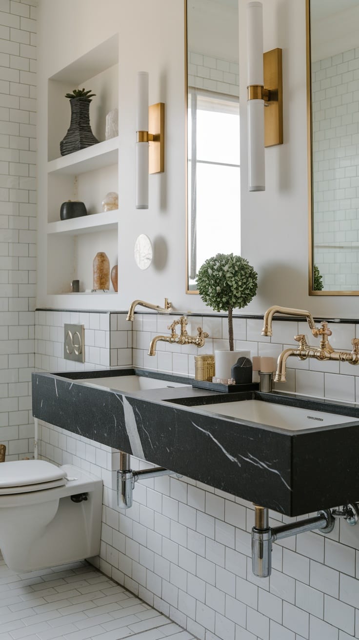 Stylish bathroom with double sinks, black stone countertop, gold fixtures, and decorative elements.