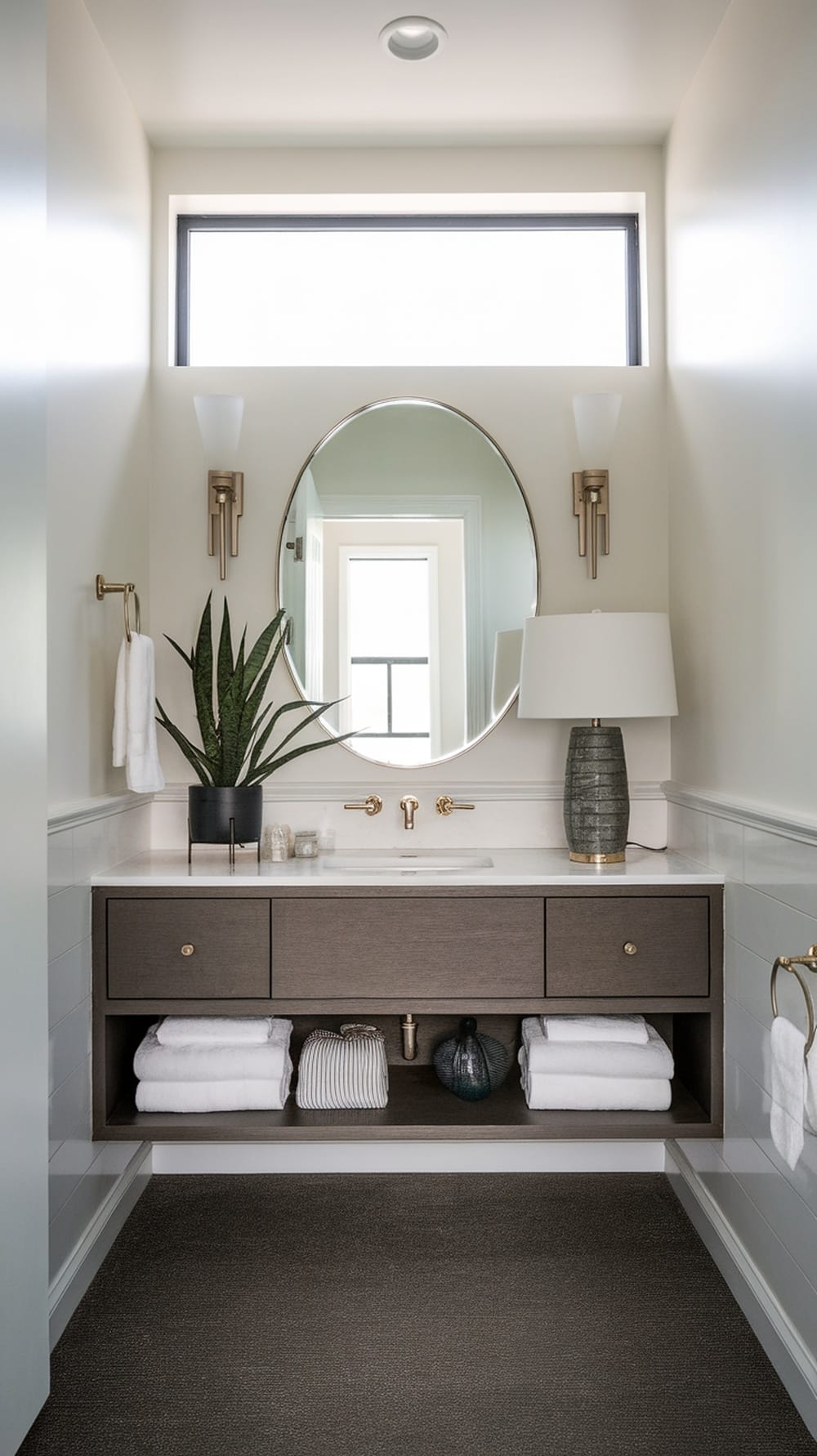 A modern floating vanity in a small ensuite, featuring a mirror, lamp, and plants, with a clean, organized look.